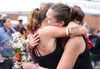 Wasilla's Amber Hays, right, hugs friend and running buddy Natalie Cadieux while holding flowers from their supporters after running the 2016 Mount Marathon Race in Seward to honor four-time 
