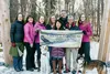 Great Land Trust employees stand in the archway of Campbell Creek Estuary Natural Area with dogs Dex and Ruby. From left to right: Mat-Su Program Director Kim Sollien, Conservation Project Ma