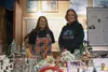 Dawn Baker and Teresa Smith smile for a photo by their joint creation, the Mistletoe Valley Christmas City display, on Dec. 2 at the Dorothy Page Museum in Wasilla. The model city will be on 