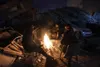 People warm up with fire in front of destroyed buildings in Antakya, southern Turkey, Wednesday, Feb. 8, 2023. With the hope of finding survivors fading, stretched rescue teams in Turkey and 