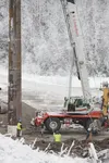 Northern Powerline Construction Inc. workers use a crane to set a power pole in place along the Old Glenn Highway Thursday afternoon. It’s one of 96 poles that will carry generation and trans