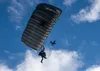 U.S. Air Force Tech. Sgt. Tyler Albee, a pararescueman assigned to the 212th Rescue Squadron, Alaska Air National Guard, glides beneath an Alaska Air National Guard HC-130J Combat King II ope
