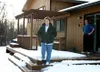 Marie Webb stands on the edge of her deck while neighbor Dan
Aldrich watches from the sliding glass door. Proposed plans to
widen the Seward Meridian Parkway would bring that road to the
corn