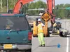 Eric Nygard keeps traffic at a slow pace along Bogard Road between Peck and Crusey streets Monday. That section of Bogard Road is getting wider lanes, merging lanes, a guardrail, two inches o