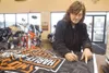 Valley resident Terry Ross takes a moment Wednesday afternoon to
write a thank you and words of encouragement for military personnel
on a Harley-Davidson flag at Denali Harley-Davidson that w