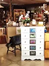 A shabby-chic dresser by Lockhart and Erskine with framed flower photos by Linda Lockhart holds some surprises inside the drawers as well and a guessing game on top (this month it is "Guess h