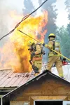 JOHN BORLAND/www.morffed.com Mat-Su firefighters John Beebe and
Tim Gonyea retreat from the roof after a successful vertical
ventilation in the roof at a house fire Wednesday at Mile 12 of
Kn