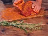 Seasoning of herbs and spices being rubbed into pork