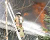 ROBERT DeBERRY/Frontiersman A member of the Mat-Su Central Fire
Department hoses down the roof of a house on Fairview Loop that
caught fire Monday afternoon. The cause of the fire is under
in