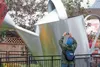 Gene Kirby — a resident of New Jersey, the ‘Garden State’ — takes a photograph with his phone of the giant watering can Thursday at the Alaska State Fair in Palmer. ROBERT DeBERRY/Frontiersma