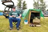 Frontiersman employee and U.S. Army veteran Dan Grota smiles with a cup of soup in front of his homemade shelter on the Alaska State Fairgrounds for Cardboard City 2015, a fundraiser for Fami