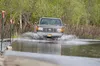 A pick-up truck navigates Sushana Drive where marker poles with pink ribbons line the edge of the street as water flows over the surface Monday afternoon. Robert DeBerry/Frontiersman.com