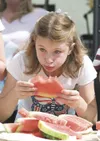 Julianna Marvin, 10, eats her way through a piece of watermelon
during the watermelon eating contest at the Fourth of July Mayor's
Picnic in Wasilla. (ROBERT DeBERRY/Frontiersman)
