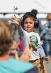 Kingston Carmack, 6 yrs old from Eagle River, throws his toy Raptor to his seated father, Aaron, at Arctic Thunder on Saturday. J. David McChesney/Frontiersman