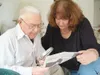 VICKI NAEGELE/For the Frontiersman Palmer resident and “Colony
Kid” Wayne Bouwens and Joan Juster use a magnifying glass to
identify people in a vintage photo reprinted in a contemporary
Midw