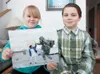Hailey, 8, and her brother Skyler, 9, proudly hold out a
photograph of their mother, 30-year-old Sgt. Jessica Ceown, sharing
a high-five with a young Afghan boy while on patrol in the town of