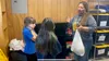 Rene Ritter (right) provides a tour of the Grizzly Cache -- a food pantry housed within Big Lake Elementary -- to student reporters Harlinn French (left) and Serenity Johnson (center). Andrew