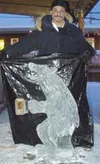 Tony Hartgrove shows off his finished carving -- a 3-foot tall
bear holding a mug of beer. yes, that is real beer in the mug,
which is also made of ice. The bear can be seen at the Great Bear