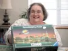 Sue Schwartz holds up the box to the 12,000-piece puzzle she is working on. Once completed, she hopes to have it framed and hung on the wall at the Chinook Villa apartments at the Wasilla Are