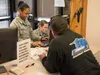 Airman 1st Class Kaylon Thomas, a 673d Security Forces Squadron Visitor Control Center technician, works with Blake Horn to renew a base visitor’s pass at the Boniface VCC at Joint Base Elmen