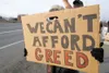 Valley resident Karen Davis peeks through a hole in her sign as
she stands along the Parks Highway near Harold J. Newcomb Park
during the Occupy Wasilla protest Saturday afternoon. (ROBERT
De