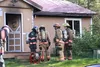 Firefighters confer at the scene of a house fire Tuesday, Aug. 19, 2015 along Amber Circle in Meadow Lakes. A neighbor spotted the fire and called authorities. While the structure wasn't a to