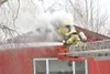 (ROBERT DeBERRY/Frontiersman) Smoke billows from a home on Lucas
Road Monday afternoon in Palmer as members of the Palmer Fire
Department use a ladder truck and chainsaw to cut an access poin
