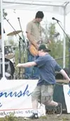 Strept's Jerry Brunnhoelzl plays guitar while a fan dances in
the makeshift mosh pit. Photo by Jeremiah Bartz/Frontiersman.