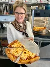 Diana Lambernakis shows off the pizza-by-the-slice option at Evangelo’s Express, which opened in May in the Crossroads Center plaza at the Seldon-Bogard roundabout near Wasilla. It is the sec