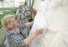 Judy Bowers checks an angel decoration before it is hoisted onto a wall at the Curtis D. Menard Memorial Sports Center in Wasilla Thursday afternoon. Volunteers with the Christmas Friendship 