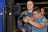 Indonesian navy Lt. Cmdr. Burhannanda Inggil Pibadhi, right, fires a lasers-guided, air-compressed, simulated 9mm Beretta pistol in the USS Missouri Small Arms Marksmanship Trainer at Recruit
