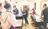 Kristin Cook, center, chef-owner of The Grape Tap in Wasilla, demonstrates cooking techniques to participants in her March cooking class. A new round of classes, featuring three different Gra