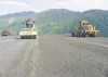 Cars cruise down the newly paved Hatcher Pass road Thursday
evening as Shelly Mullican, left, in a dirt compactor and Mike
Tallon in a scraper prepare a pullout for a layer of asphalt. Photo
