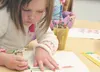 Machetanz Elementary School kindergarten student Avery Gayman concentrates while creating a card to put in a Veterans Day care package for soldier Anthony Galvin. HEATHER A. RESZ/Frontiersman