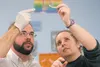 Cook Inlet Aquaculture Association biologist Nathan Weber talks about the cleithrum of a northern pike as Lesley Bunch holds it up to the light for her seventh-grade students at Palmer Junior