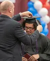 Certified Nurse Assistant graduate Anthony Aguiar has his cap fixed by Don Young Job Corps Center director Bobbie Irvin after Irvin accidentally pulled the tassel off the cap during the schoo