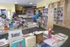Books on sale sit on tables as Valley resident Kay Hall looks
through the shelves at Pandemonium Booksellers and Cafe during
their last day of business at their old location near Home Depot.
