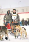 Willow musher Rick Holt rounds the the corner of Fourth Avenue
onto Cordova Street at as his helper controls the rear sled and his
Iditarider enjoys the ride during the ceremonial start of th