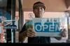 Alfredo Sibucao Jr., a retired Air Force technical sergeant, flips the open sign at his retail store in Las Vegas, June 22, 2015. Sibucao retired from the Air Force in 2014 and now owns and o