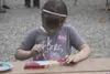 Six-year-old Brooklyn Lausier concentrates while painting a wooden fish at Saturday's annual Palmer Hay Flats Summer Festival at Reflections Lake. Lausier said she was painting a salmon, whil