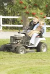 Kelsey retherford and her son Tyler duck to avoid some branches
while mowing the lawn Monday along the Palmer-Wasilla Highway.
Tyler was helping supervise the operation. ROBERT
DeBERRY/Fronti