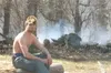 MICHAEL ROVITO/Frontiersman Parker Strickland sits in front of
smoldering brush Wednesday after sparks from a fire pit ignited a
wildfire that consumed about two acres.