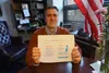 Rep. Andrew Gray, D-Anchorage, in his Capitol office on May 16, 2024, holds up a printout showing how warning signs about alcohol consumption's health effects would change under legislation h