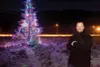 Jason, one of the tree keepers, stands next to the lit tree
along the Glenn Highway. (ROBERT DeBERRY/Frontiersman)