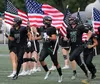 Colony seniors Tegan Olson, Eli Whitworth and Matthew Ross lead their team onto the field carrying American flags prior to hosting West Anchorage during the program's annual military apprecia