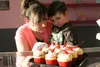Sugar High owner Tabitha Pedalino and her 2-year-old son inspect a tray of Strawberry Champagne and Birthday Cake cupcakes at the new sweet shop in the Frontier Mall in Wasilla, open 11 a.m. 