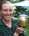 Tracy, a participant in Janet Schofield's annual herb workshop
in Palmer, holds a jar of salve infused with devil's club,
cottonwood, and Arnica flowers. A night of cooking will make this
sal