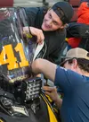 Haaken Wold, 19, veteran Iron Dog racer, works with friend Hayden Reid, both of Wasilla, to apply sponsor decals to of one the team's snowmachines at the Menard Center Wednesday afternoon. J.