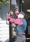 Alaska State Trooper Dave Wilson checks for fingerprints on the
door at Susitna Professional Pharmacy on Thursday following a
robbery at the store. Photo by STEVE KADEL/Frontiersman.