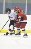 Houston defenseman Max Natekin battles for the puck against Wasilla’s Adam Apangalook during Friday’s game at the Curtis C. Menard II Memorial Hockey Tournament. ROBERT DeBERRY/Frontiersman.c
